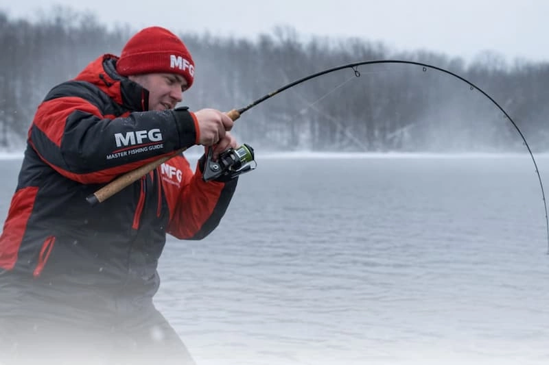Best winter pike fishing rod in action — angler in MFG jacket fighting big pike with bent rod in freezing conditions — check price & top picks