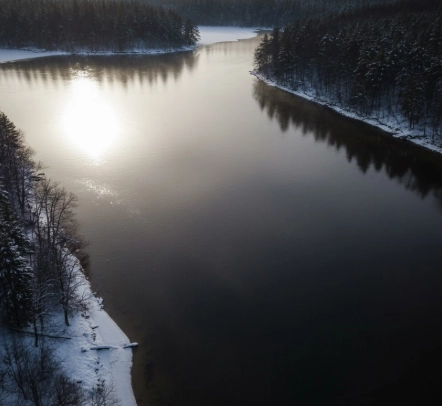 Aerial winter view of an unfrozen lake showing how sunlight and clouds change pike water clarity, with bright clear water on one side and darker shaded water on the other