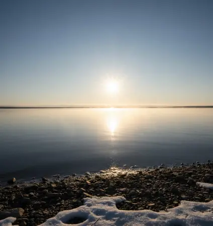 February pike fishing feeding window — midday winter sun over cold lake surface