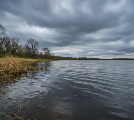 Best Time to Catch Pike in Spring – dark pre-front clouds and wind-blown shoreline signaling falling pressure and expanding feeding window