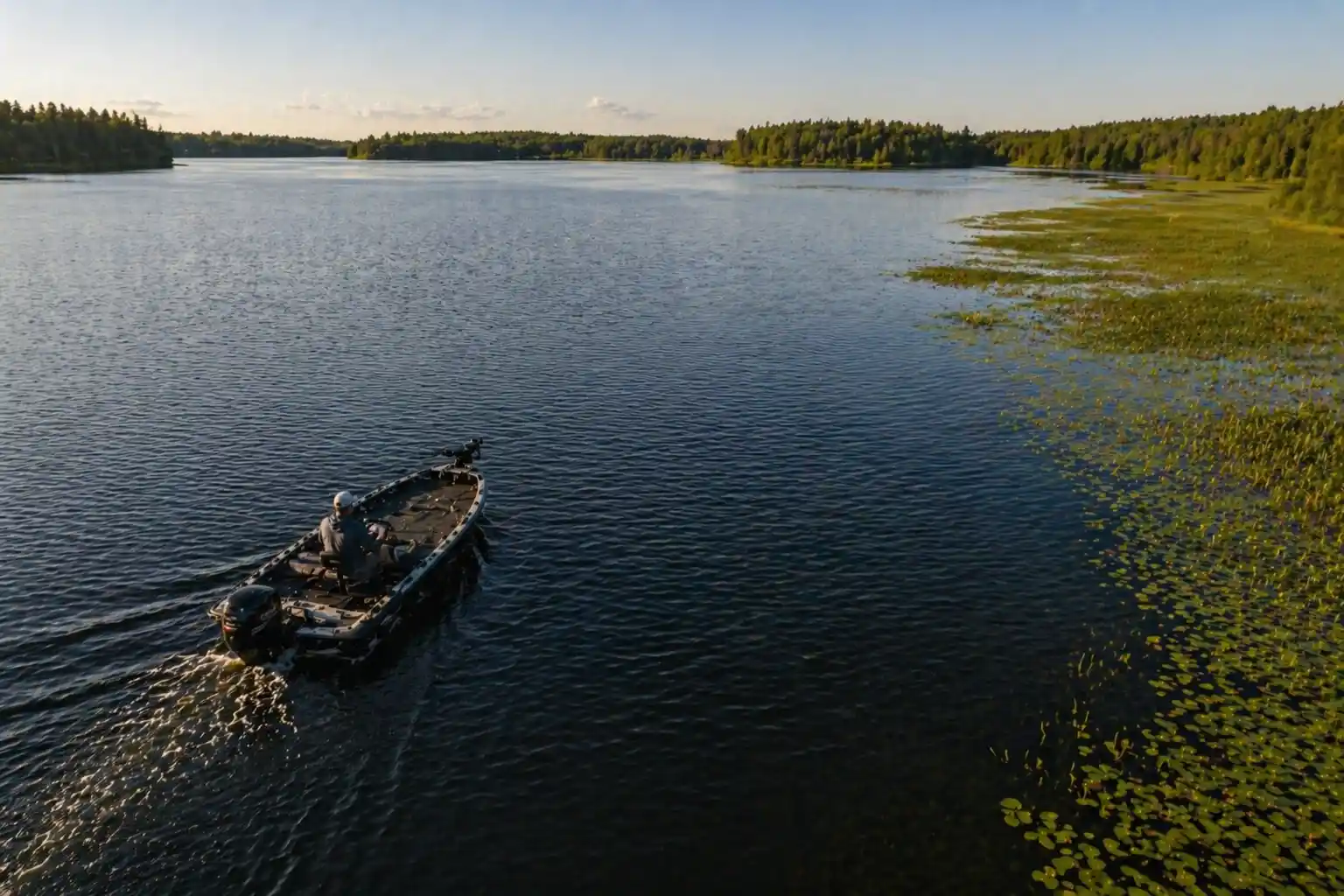 Fishing boat repositioning away from the weed edge in summer, showing when to leave dead water and move toward active pike zones