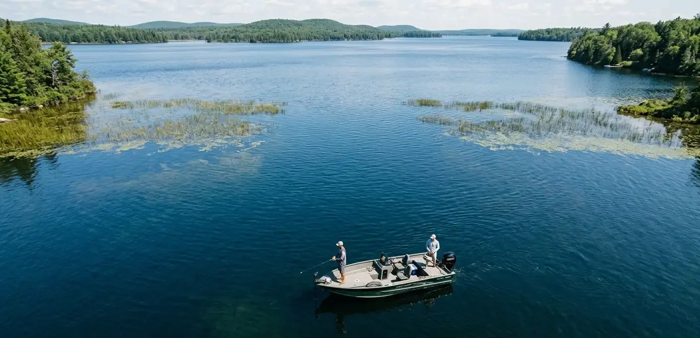 A fishing boat positioned at a distance from lake vegetation, showing how to catch pike from a boat in summer through better boat control