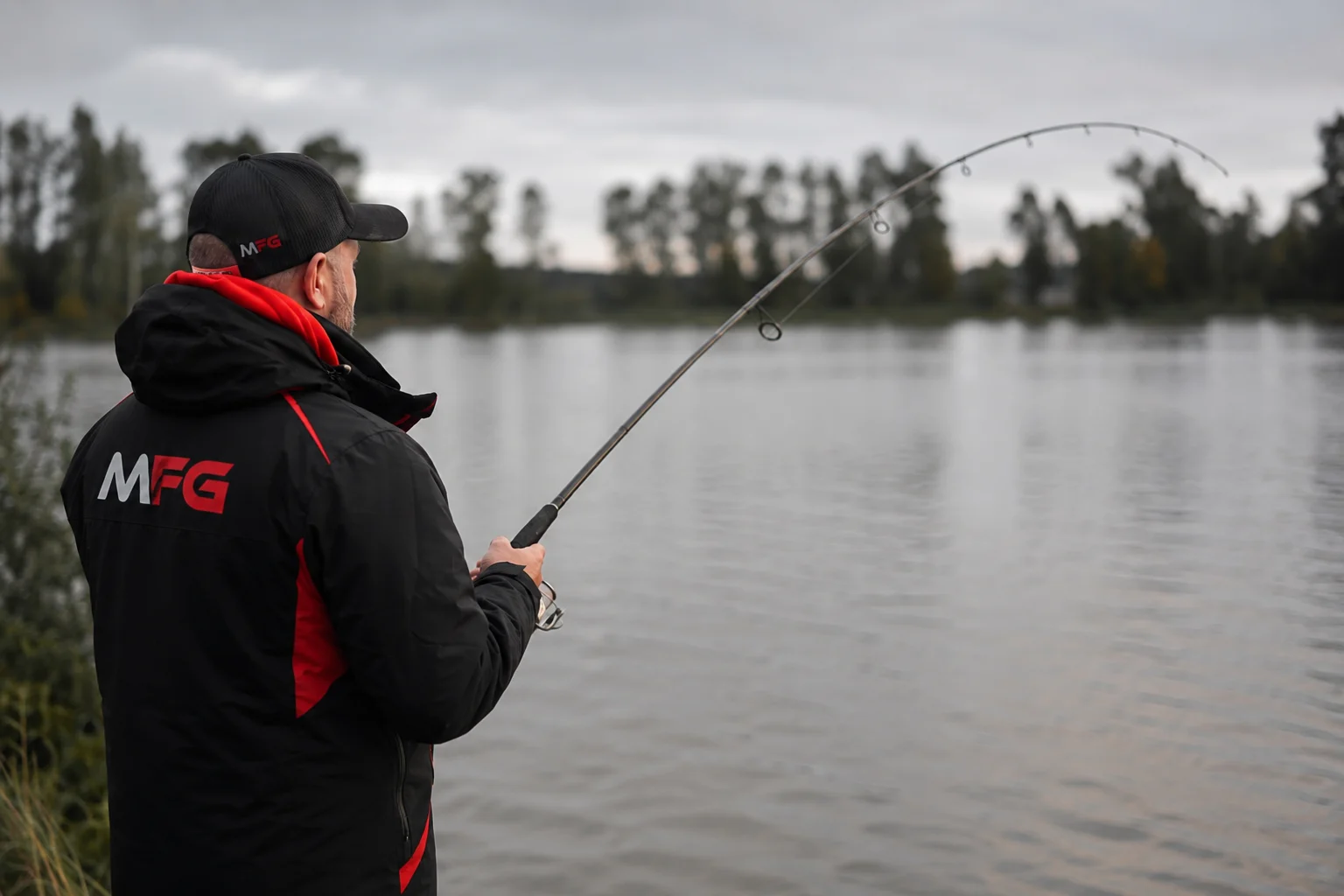 Angler holding a pike fishing rod on the water's edge — how to choose a pike fishing rod guide
