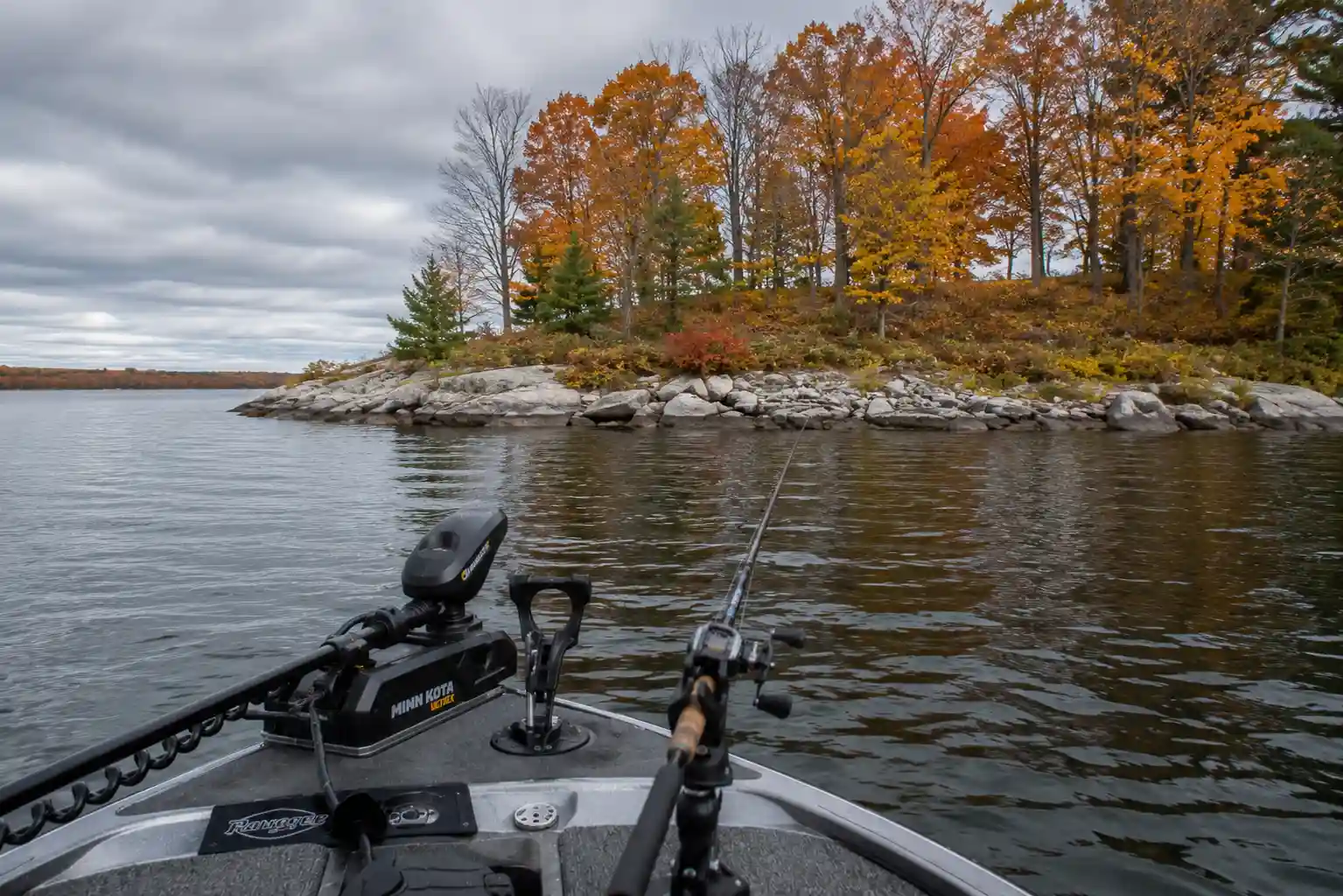 Boat positioned on open water near a rocky point during mid-fall pike fishing