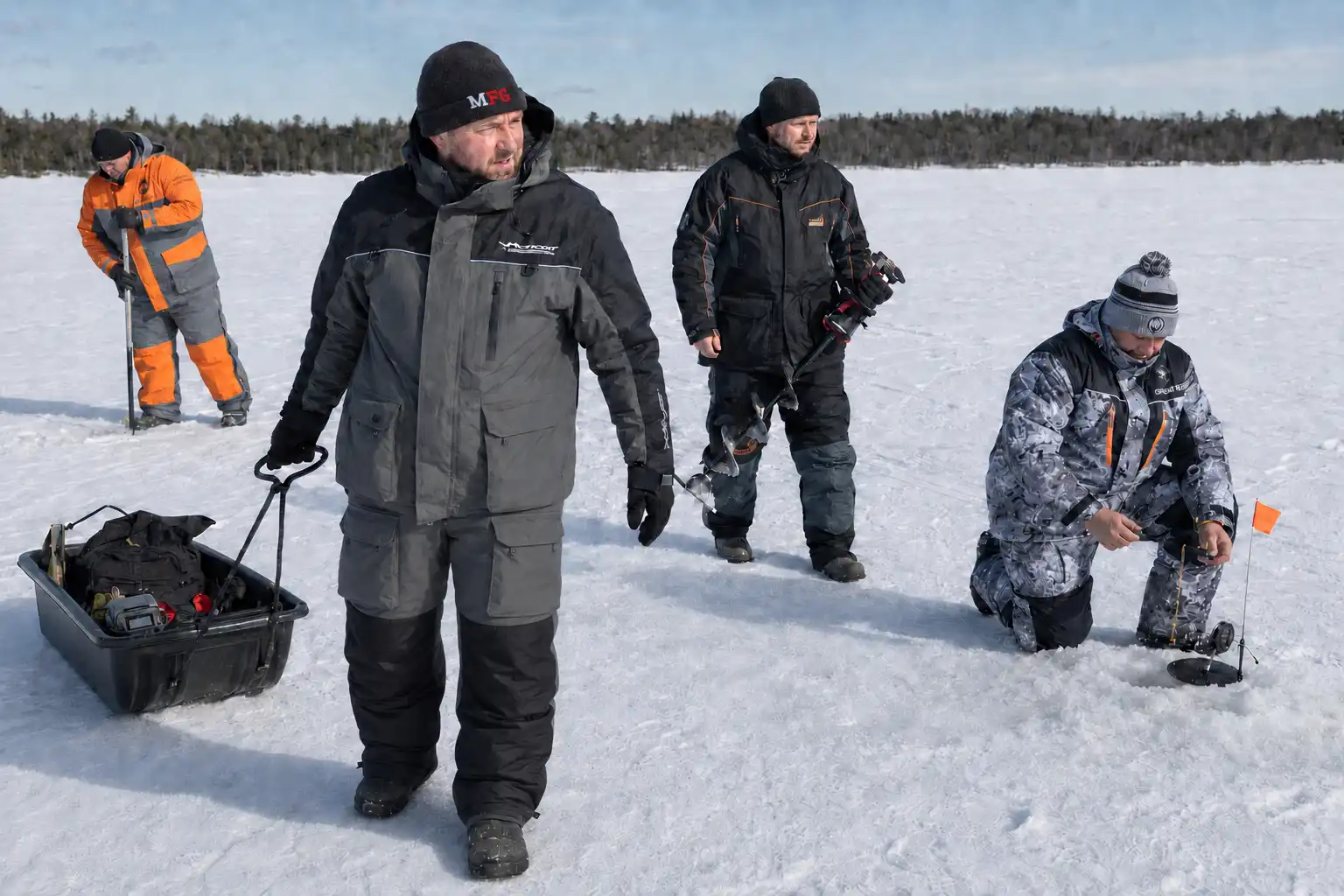 MFG testers wearing floating ice fishing suits while setting tip-ups on frozen lake ice