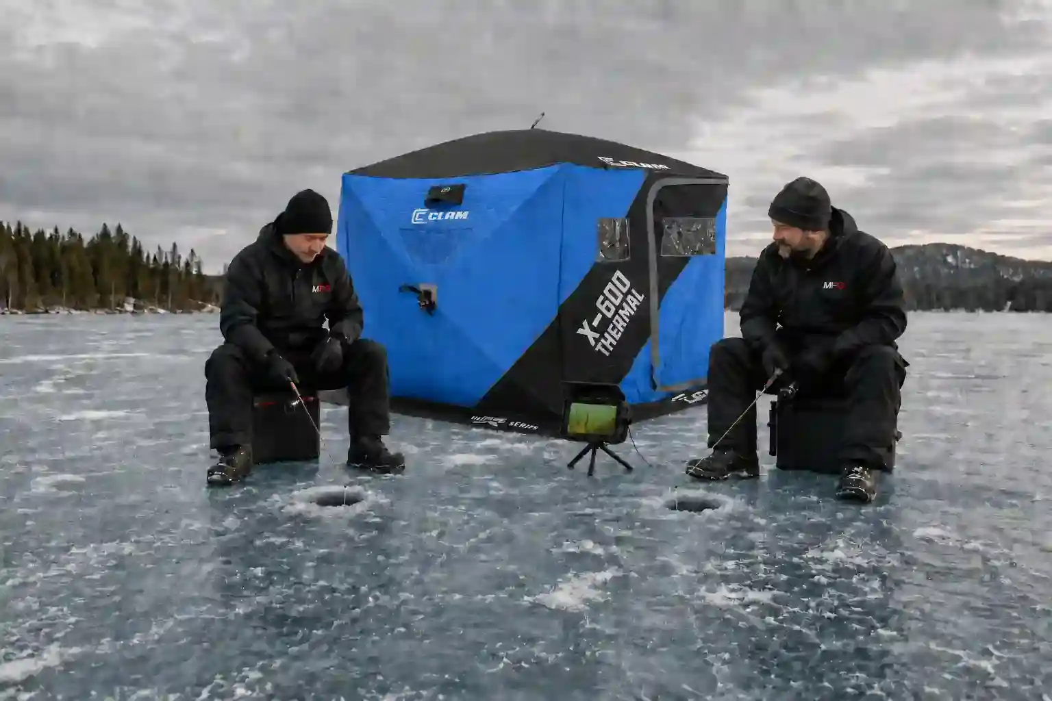Underwater fishing camera monitor on a tripod between two MFG anglers ice fishing beside a shelter