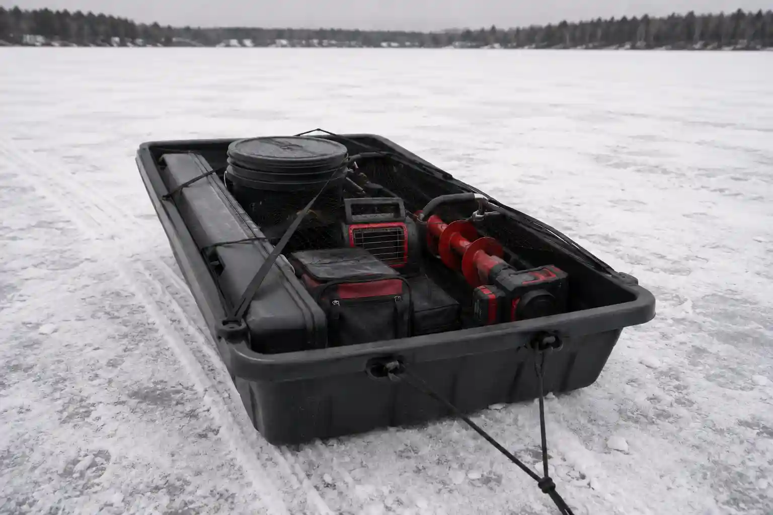 Ice fishing sled loaded low and balanced with secured auger, heater, bucket, and rod case