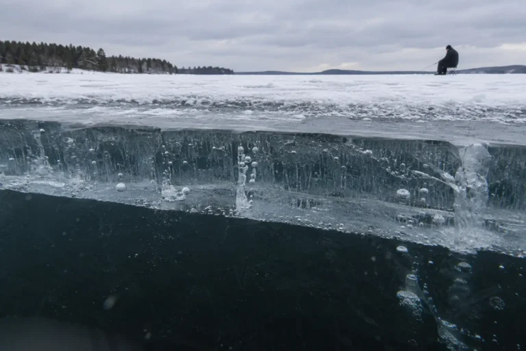 Ice fishing safety on thick clear ice with an MFG angler fishing in the distance